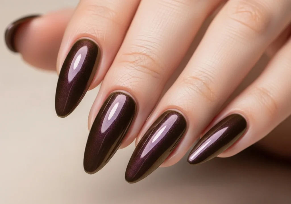 Close-up of glossy chocolate brown nails with a mesmerizing pearlescent chrome finish reflecting soft light.