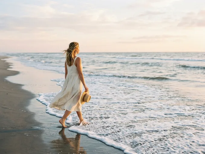 Woman walking barefoot along the beach during an earthing session