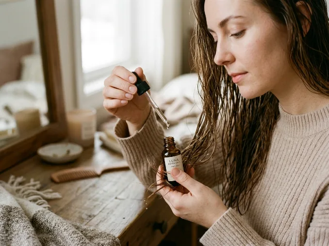 Woman applying hair oil to reduce winter frizz